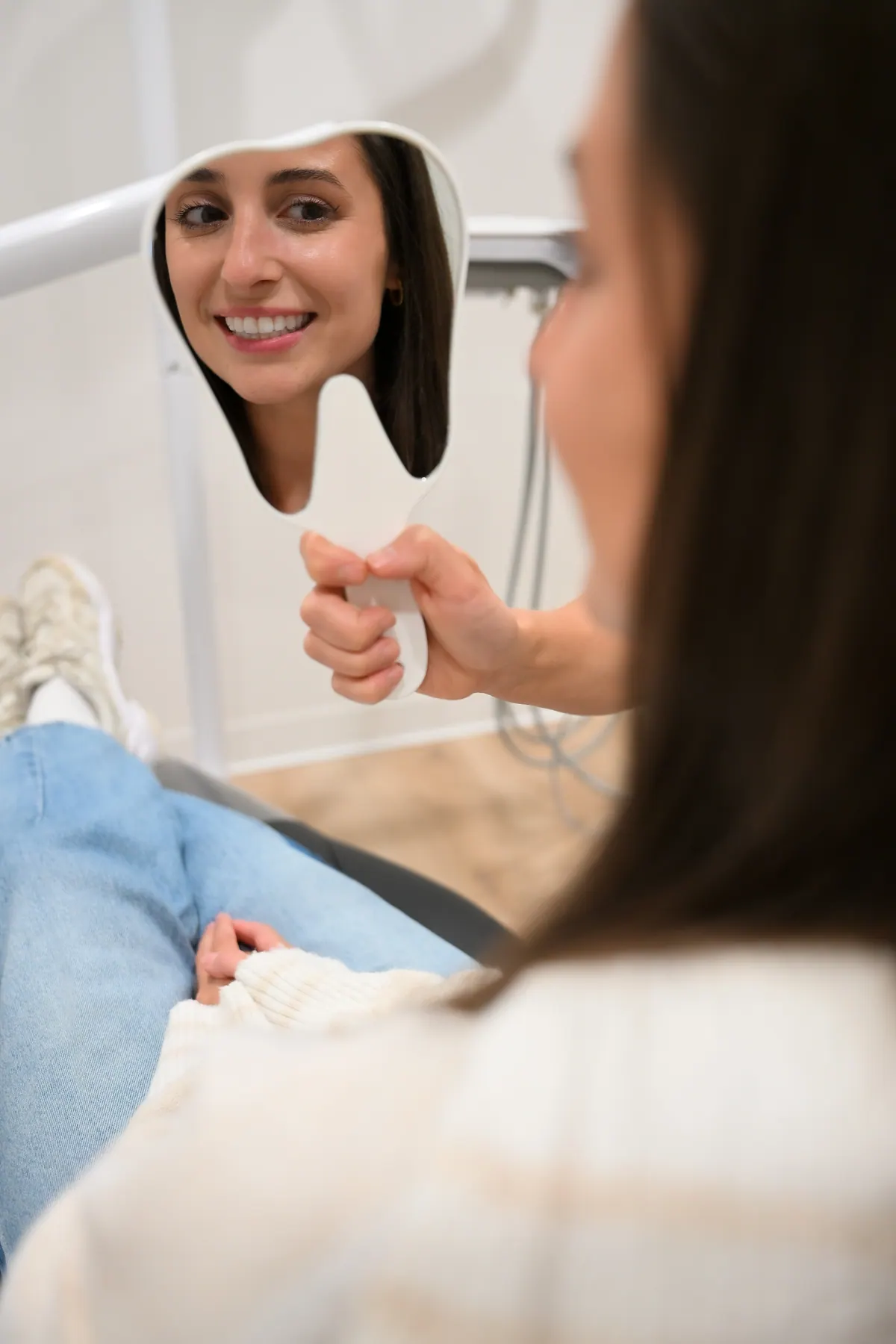 A patient smiling at her reflection in a hand mirror