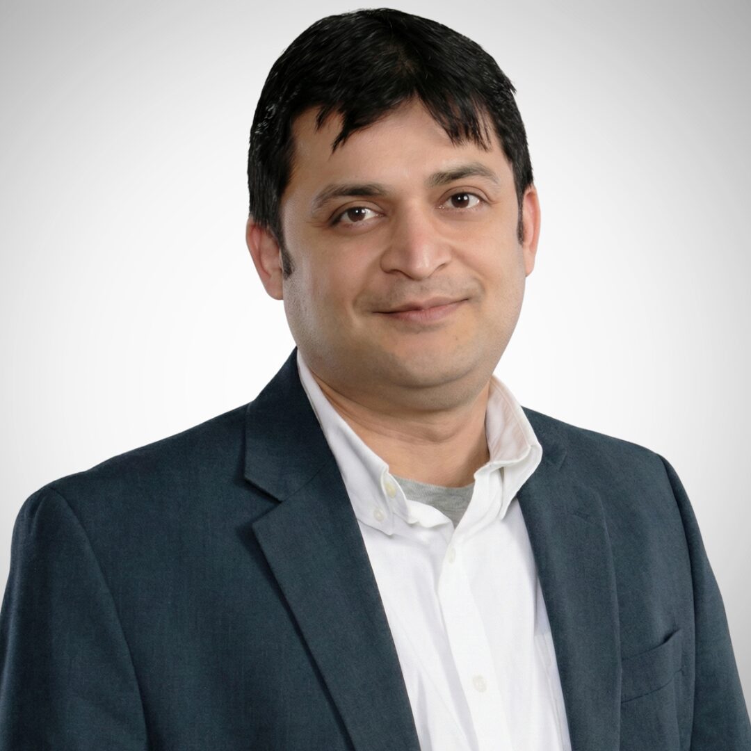 A person in a blue blazer and white shirt smiles against a plain white background. No landmarks or historical buildings are visible.