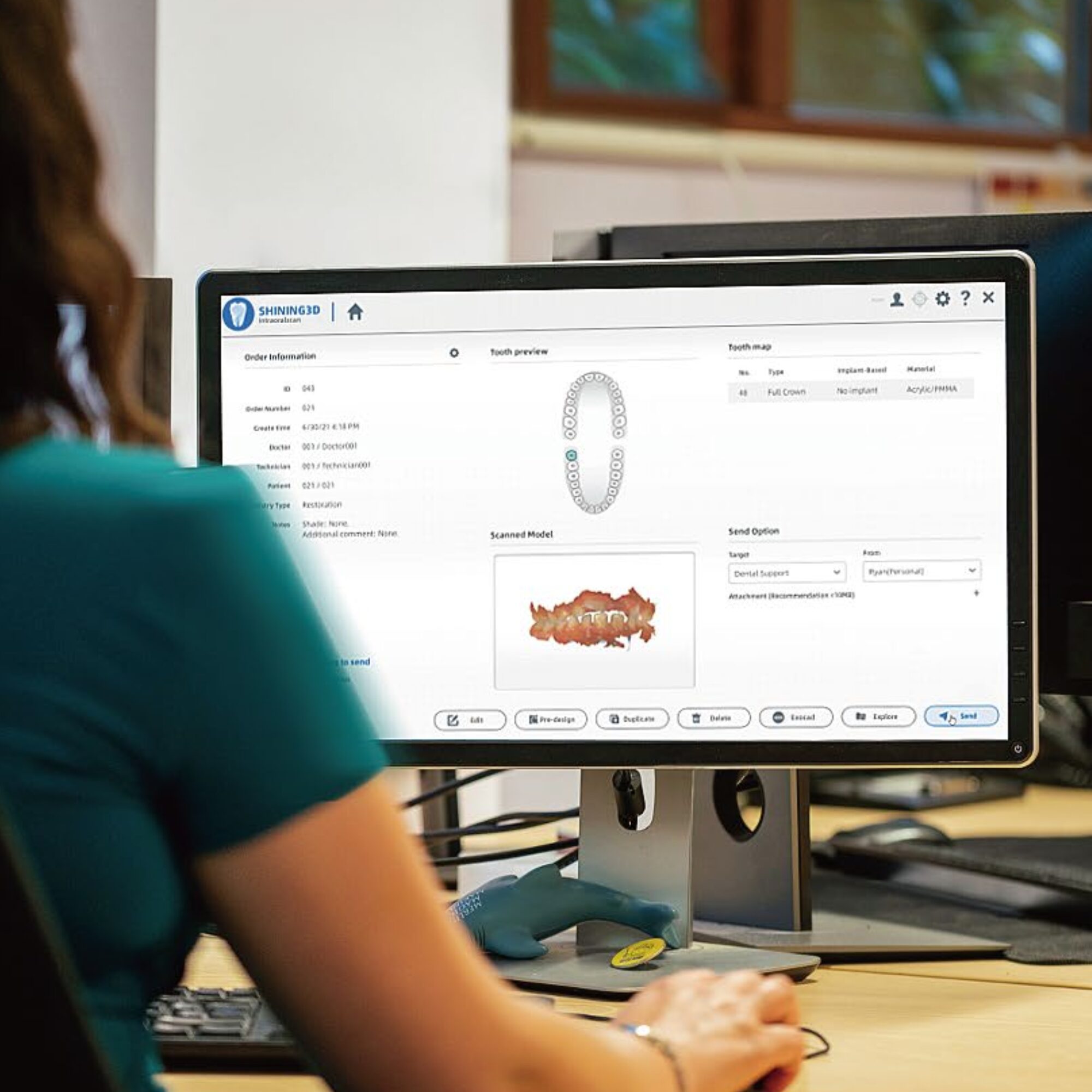 A person uses a computer to view dental software, featuring a digital tooth model and scanning device, in an office setting.
